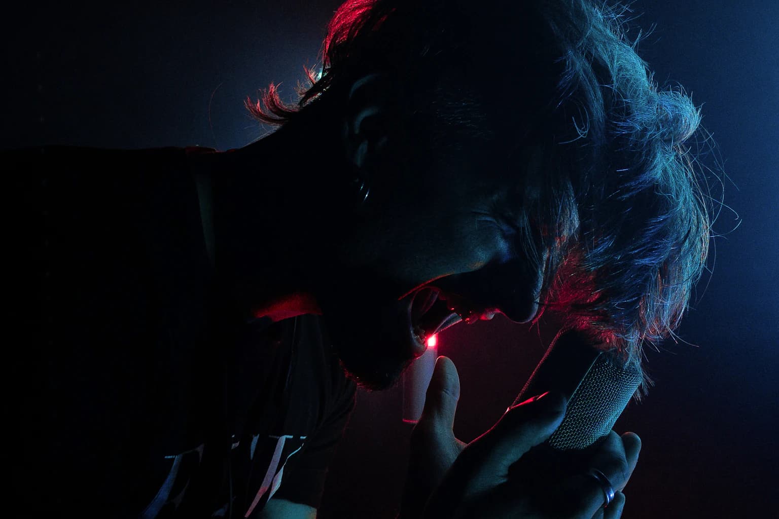 Singer holding a microphone under red and blue stage light