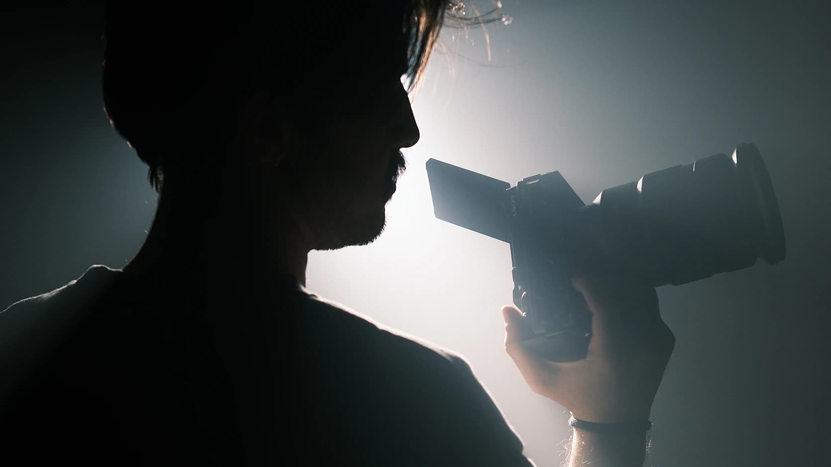 Photographer holding a camera in dramatic backlight